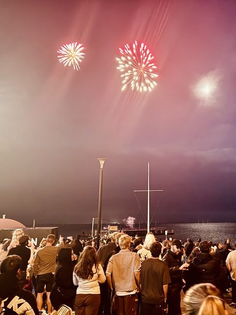 Crowd watching fireworks explode over a night sky