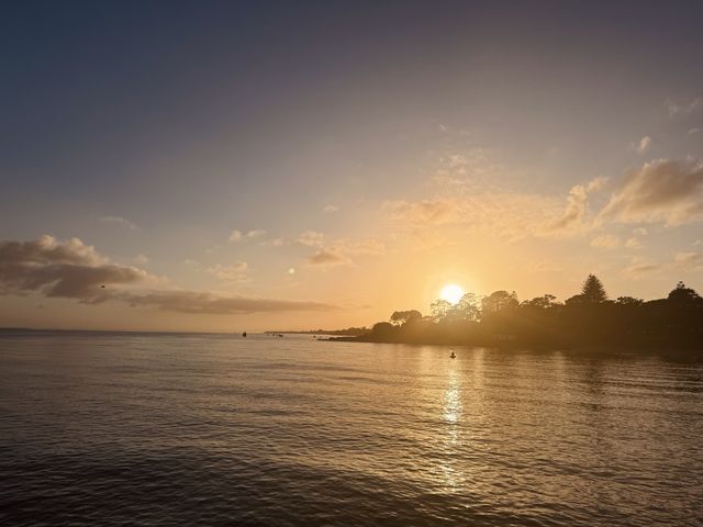 Sun setting behind clouds over still water